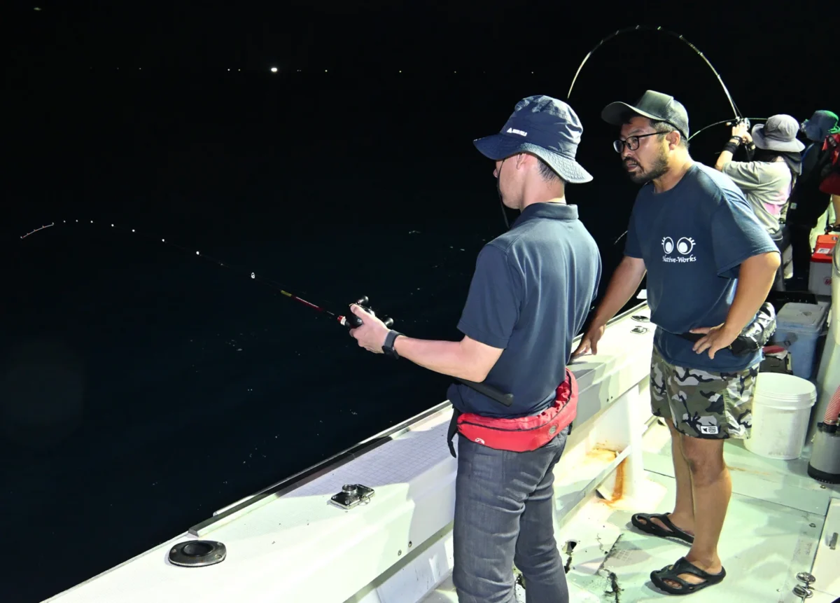 金沢・金石港から出航するイカ釣り漁船で客にイカ釣りを教える高根さん（撮影：2025年7月　加藤直人）