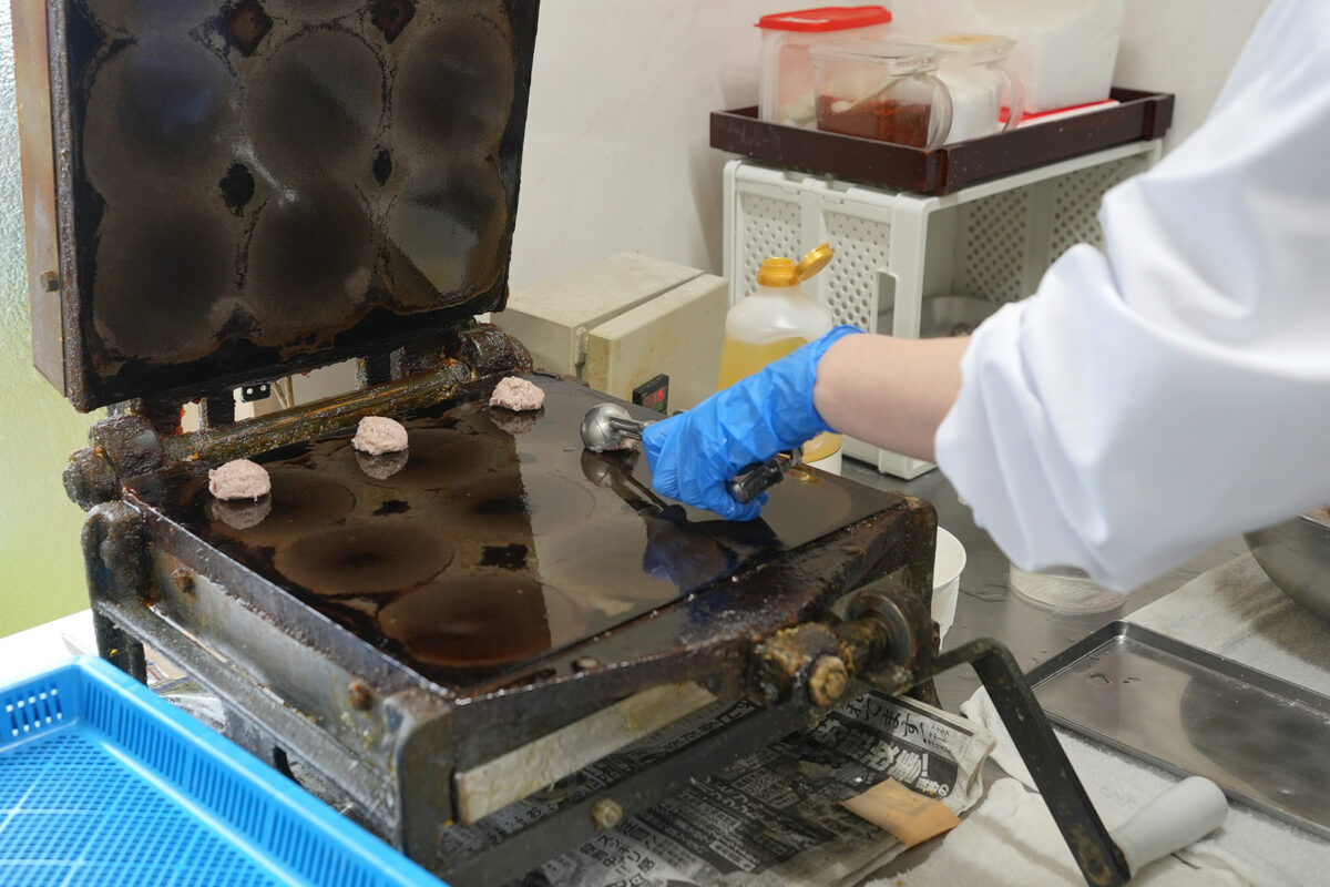 「能登いか煎餅」の製造工程。小さく丸めた生地を専用の焼き機に並べる(撮影:2026年3月 関口威人)